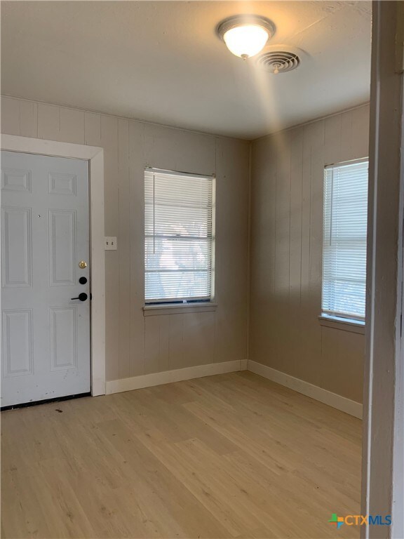 foyer entrance featuring wooden walls and light wood-type flooring