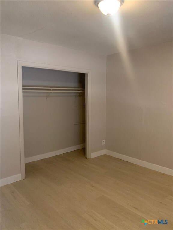 unfurnished bedroom featuring a closet and light wood-type flooring