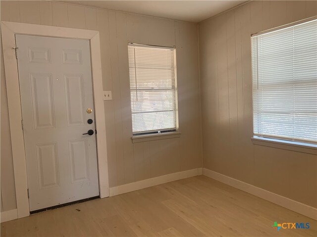 doorway featuring wooden walls and light hardwood / wood-style floors