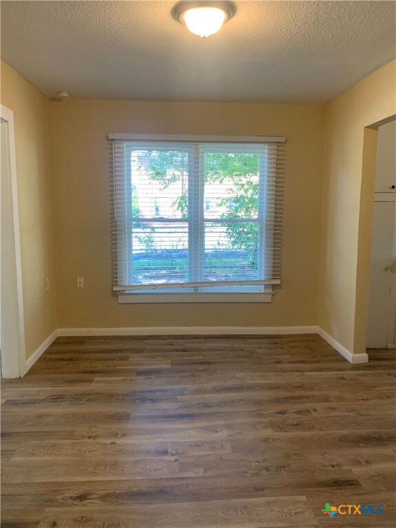 unfurnished room featuring dark wood-type flooring and a textured ceiling