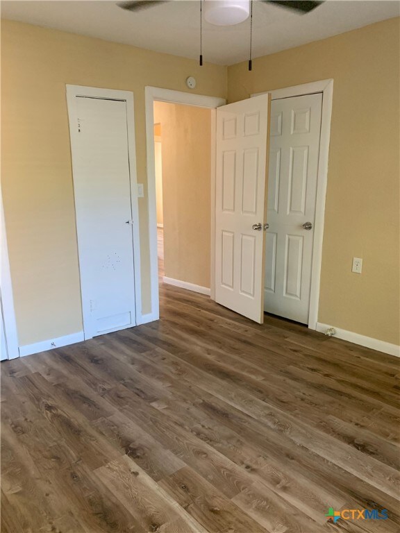 unfurnished bedroom with dark wood-type flooring and ceiling fan