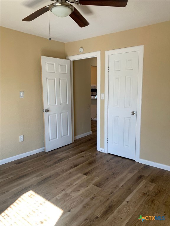 unfurnished bedroom with dark wood-type flooring and ceiling fan