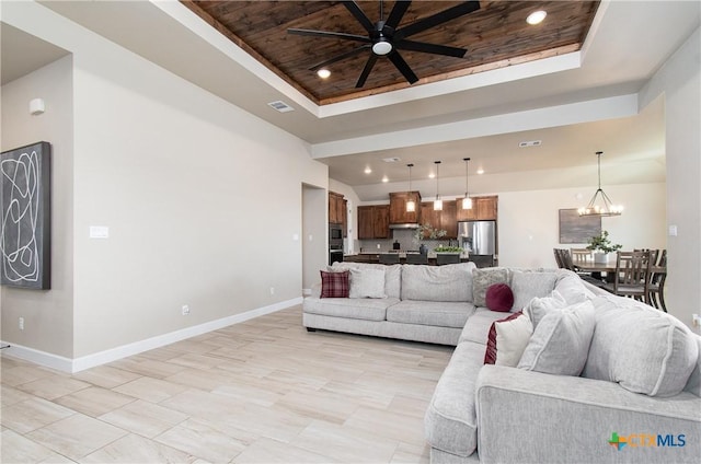 living room featuring a raised ceiling, wood ceiling, and ceiling fan with notable chandelier