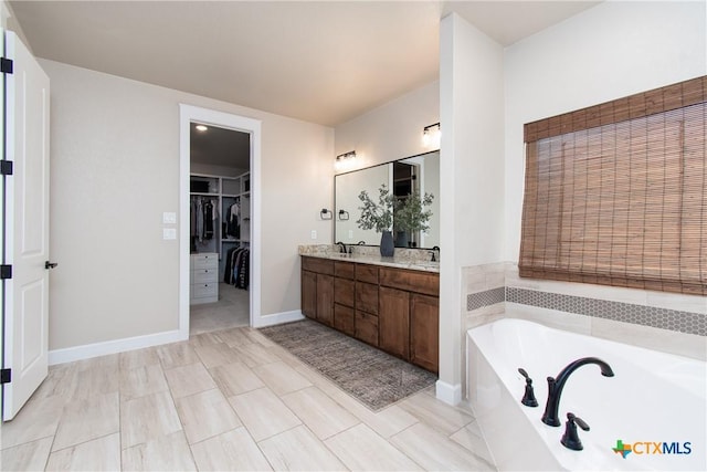 bathroom with vanity and tiled bath