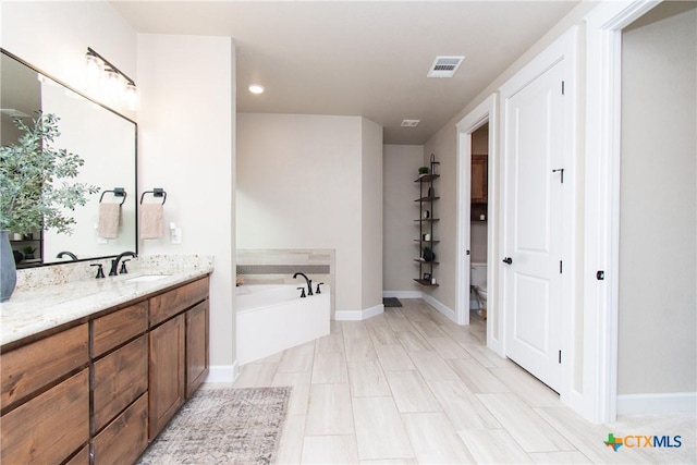 bathroom with vanity, a tub to relax in, and toilet