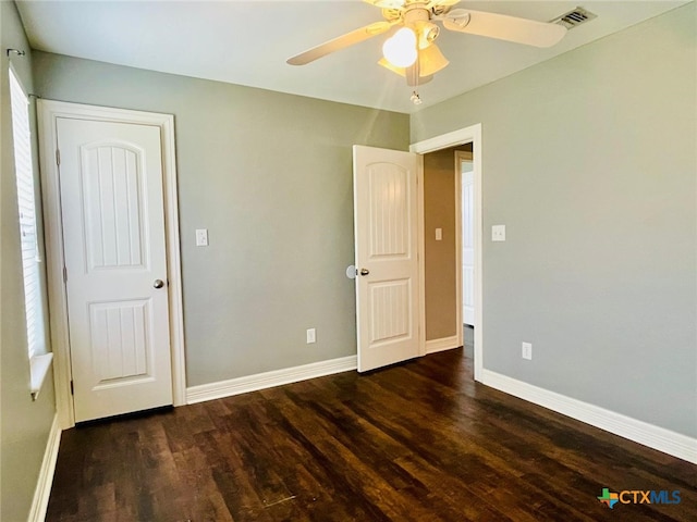 unfurnished bedroom with ceiling fan and dark wood-type flooring