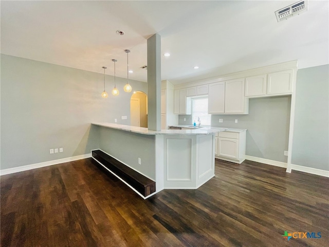 kitchen with kitchen peninsula, dark wood-type flooring, white cabinets, and pendant lighting