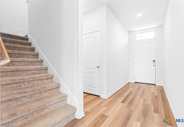 entrance foyer with stairway, baseboards, and light wood finished floors