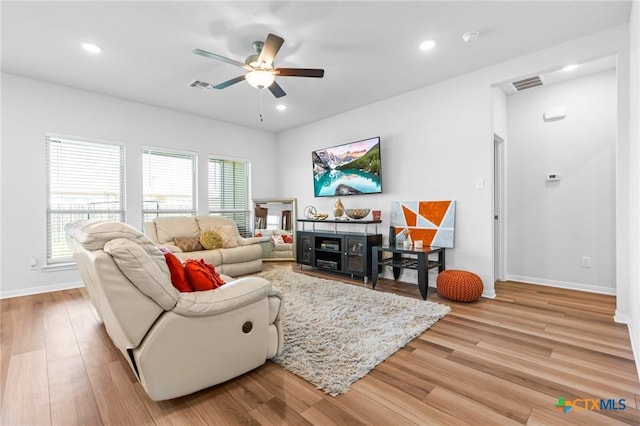 living area with visible vents, light wood-style flooring, baseboards, and a ceiling fan