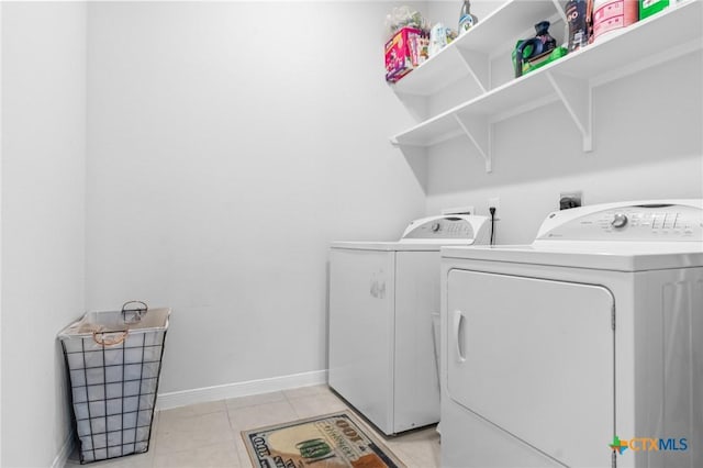 laundry room with washing machine and clothes dryer, laundry area, baseboards, and light tile patterned floors