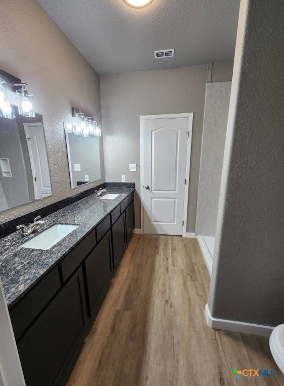 full bathroom featuring visible vents, wood finished floors, a sink, and double vanity