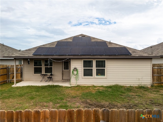 rear view of house featuring a patio, solar panels, and a lawn