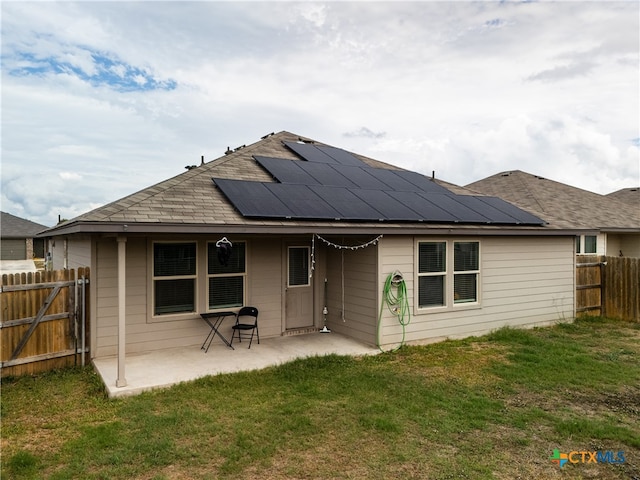 back of house with a lawn, solar panels, and a patio