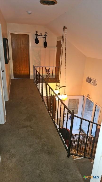 hall with lofted ceiling and dark colored carpet