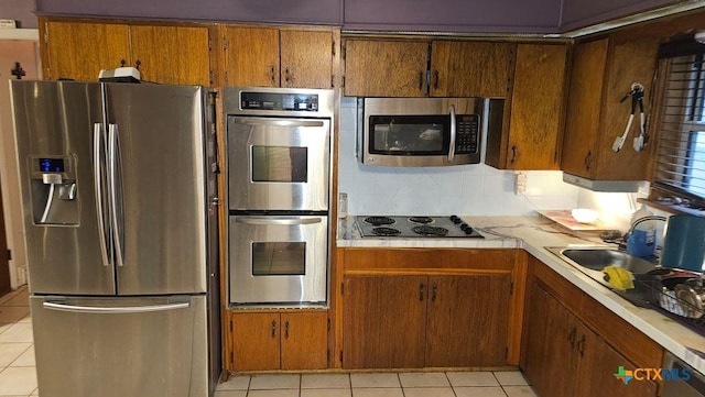 kitchen featuring light tile patterned flooring, stainless steel appliances, sink, and decorative backsplash