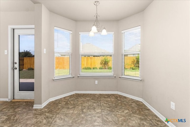 unfurnished dining area with an inviting chandelier, baseboards, and a wealth of natural light