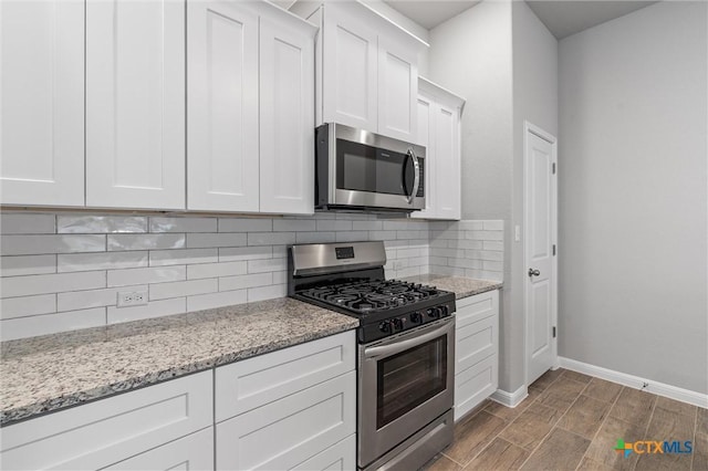 kitchen with light stone countertops, decorative backsplash, stainless steel appliances, and white cabinets