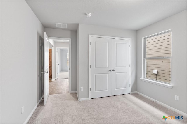 unfurnished bedroom featuring light colored carpet and a closet