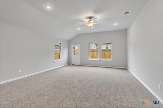 empty room with lofted ceiling, light colored carpet, and ceiling fan