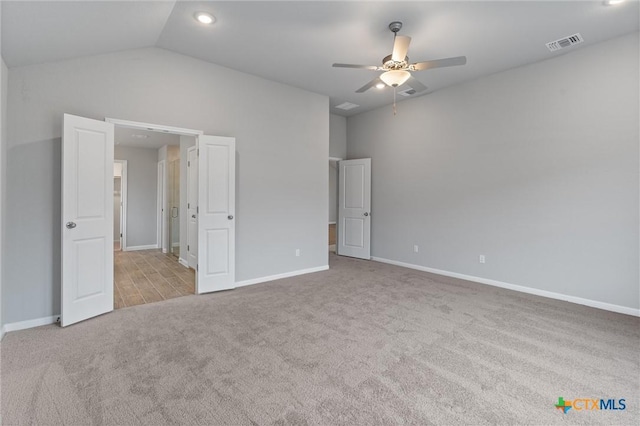 unfurnished bedroom with ceiling fan, lofted ceiling, and light carpet