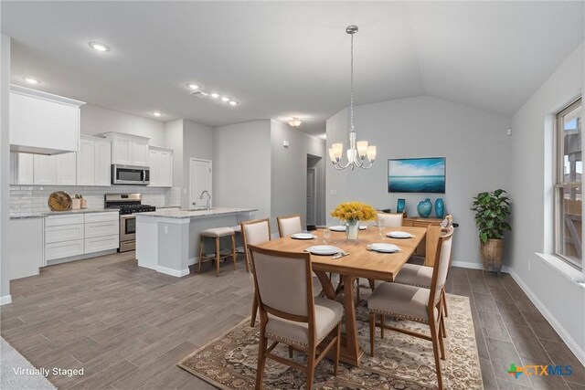 kitchen with appliances with stainless steel finishes, an island with sink, sink, white cabinets, and light stone counters