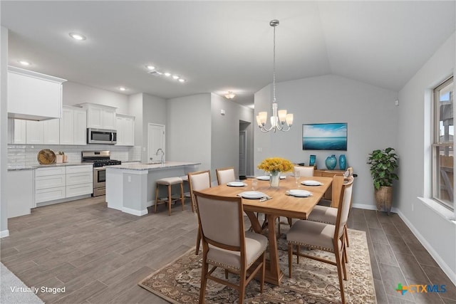 dining room featuring lofted ceiling, sink, and an inviting chandelier