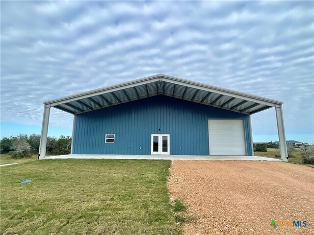 view of outbuilding featuring a garage, a lawn, and french doors