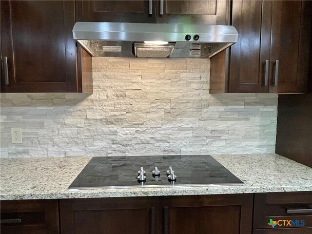 kitchen with dark brown cabinets, extractor fan, decorative backsplash, and light stone counters