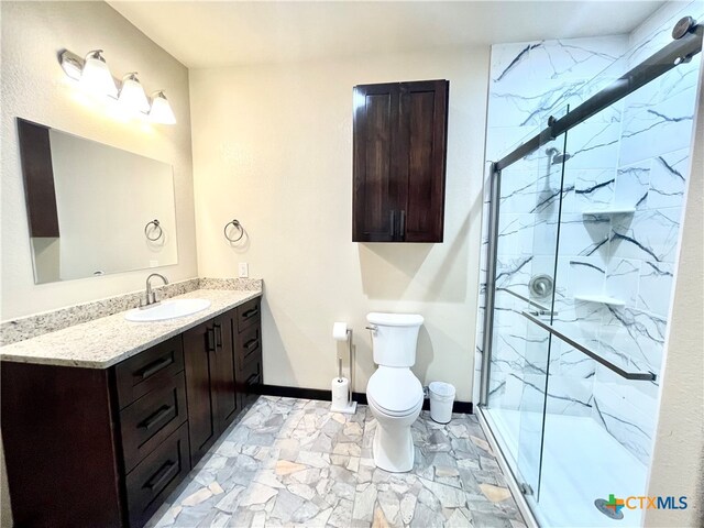 bathroom featuring toilet, vanity, and a shower with shower door