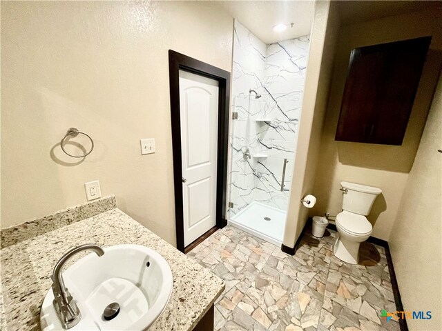 bathroom with toilet, vanity, and a tile shower