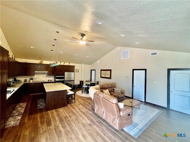 living room featuring light hardwood / wood-style floors, ceiling fan, a textured ceiling, and high vaulted ceiling