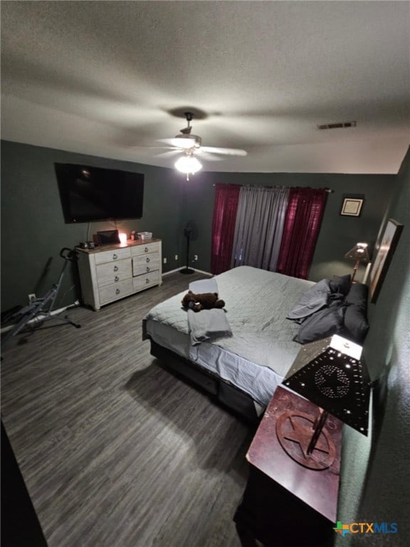 bedroom with ceiling fan, wood-type flooring, and a textured ceiling