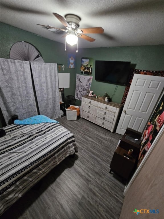 bedroom featuring ceiling fan, dark hardwood / wood-style flooring, and a textured ceiling