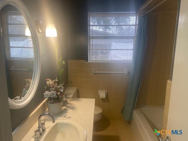 full bathroom featuring vanity, toilet, shower / bath combo with shower curtain, and tile walls