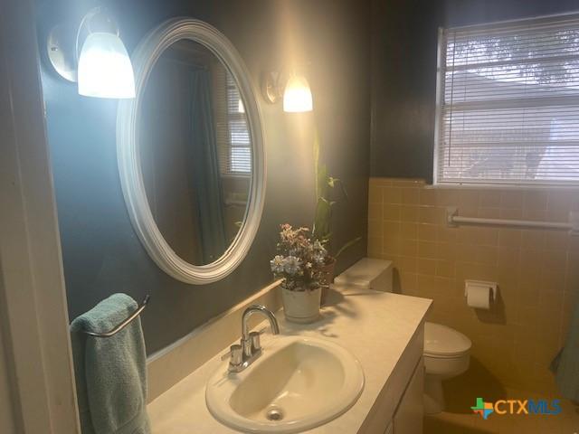 bathroom featuring vanity, tile walls, and toilet