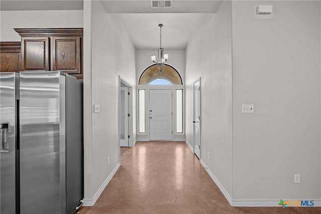 foyer entrance featuring a notable chandelier, baseboards, visible vents, and finished concrete floors