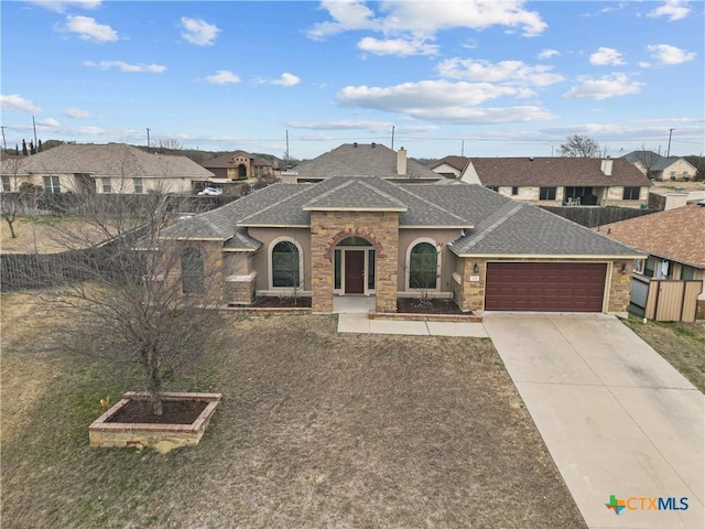 view of front of property featuring a garage, concrete driveway, a shingled roof, and a residential view