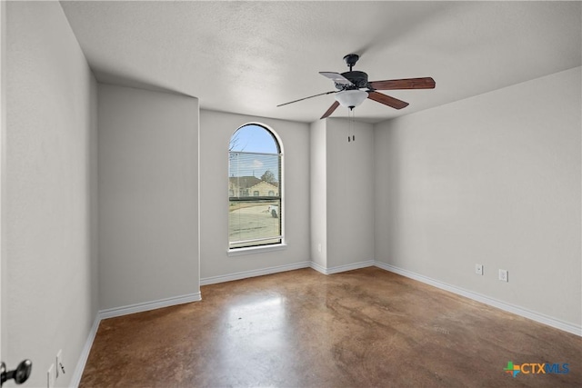 empty room featuring ceiling fan, concrete floors, baseboards, and a textured ceiling