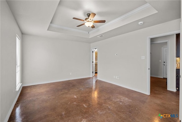 unfurnished room with baseboards, a tray ceiling, and concrete flooring