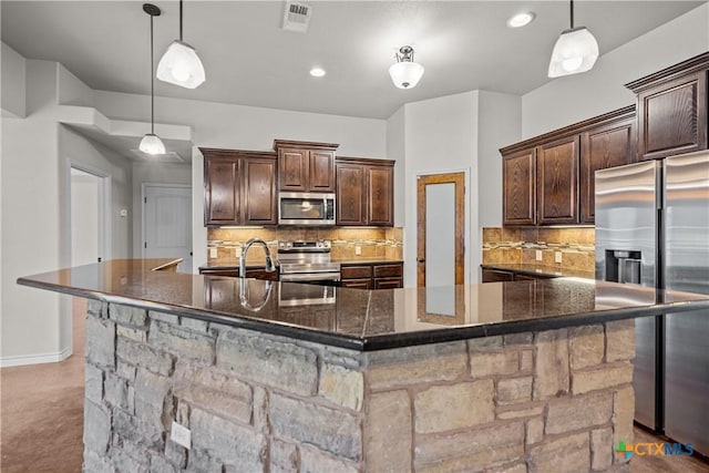 kitchen with appliances with stainless steel finishes, visible vents, dark brown cabinetry, and tasteful backsplash