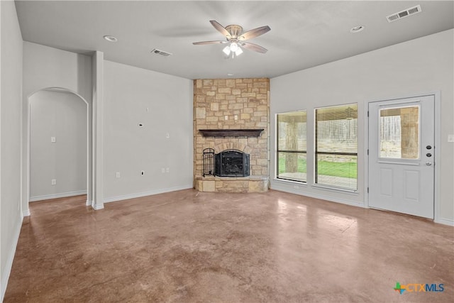 unfurnished living room featuring finished concrete floors, visible vents, arched walkways, and a stone fireplace