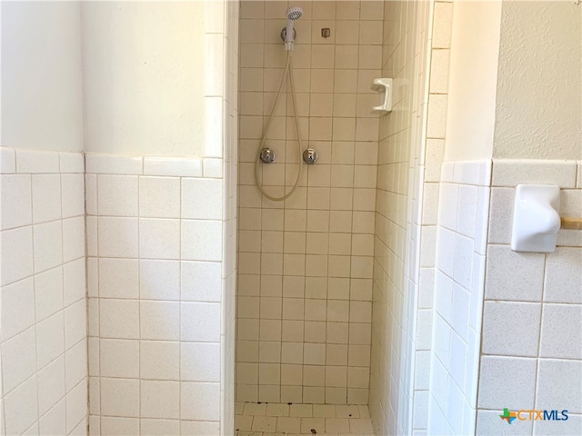 bathroom featuring tiled shower and tile walls