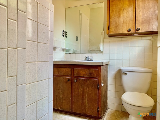 bathroom with vanity, toilet, and tile walls