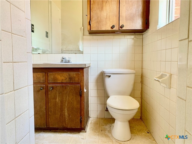 bathroom featuring vanity, tile walls, and toilet