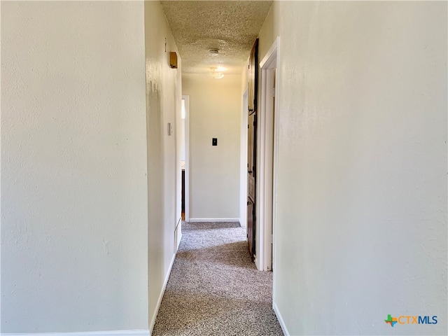 hallway featuring light carpet and a textured ceiling