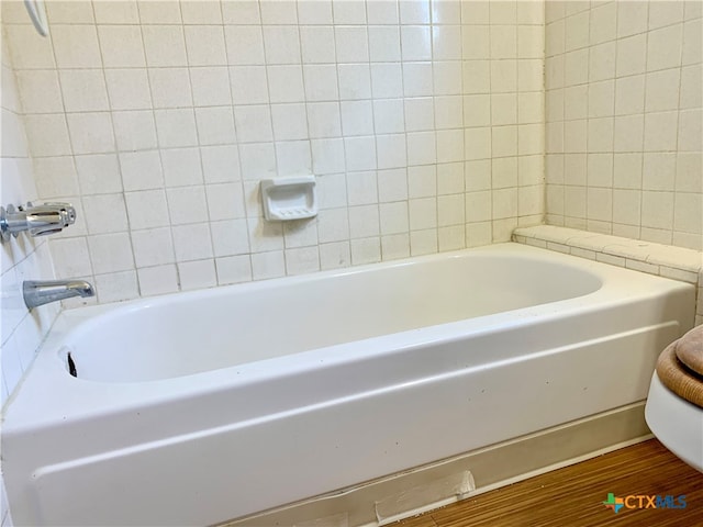 bathroom with hardwood / wood-style floors and a bath