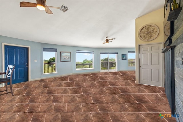 unfurnished living room featuring dark tile patterned flooring and ceiling fan