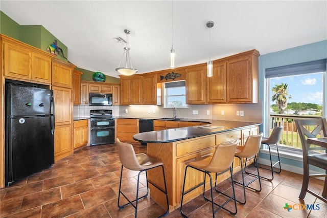 kitchen with vaulted ceiling, sink, a breakfast bar area, hanging light fixtures, and black appliances