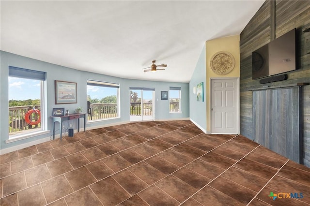 interior space featuring ceiling fan, dark tile patterned flooring, vaulted ceiling, and a wealth of natural light