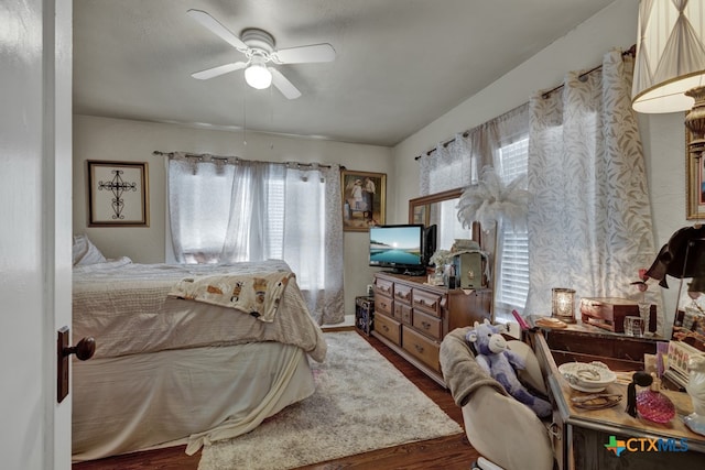 bedroom featuring ceiling fan, multiple windows, and wood-type flooring